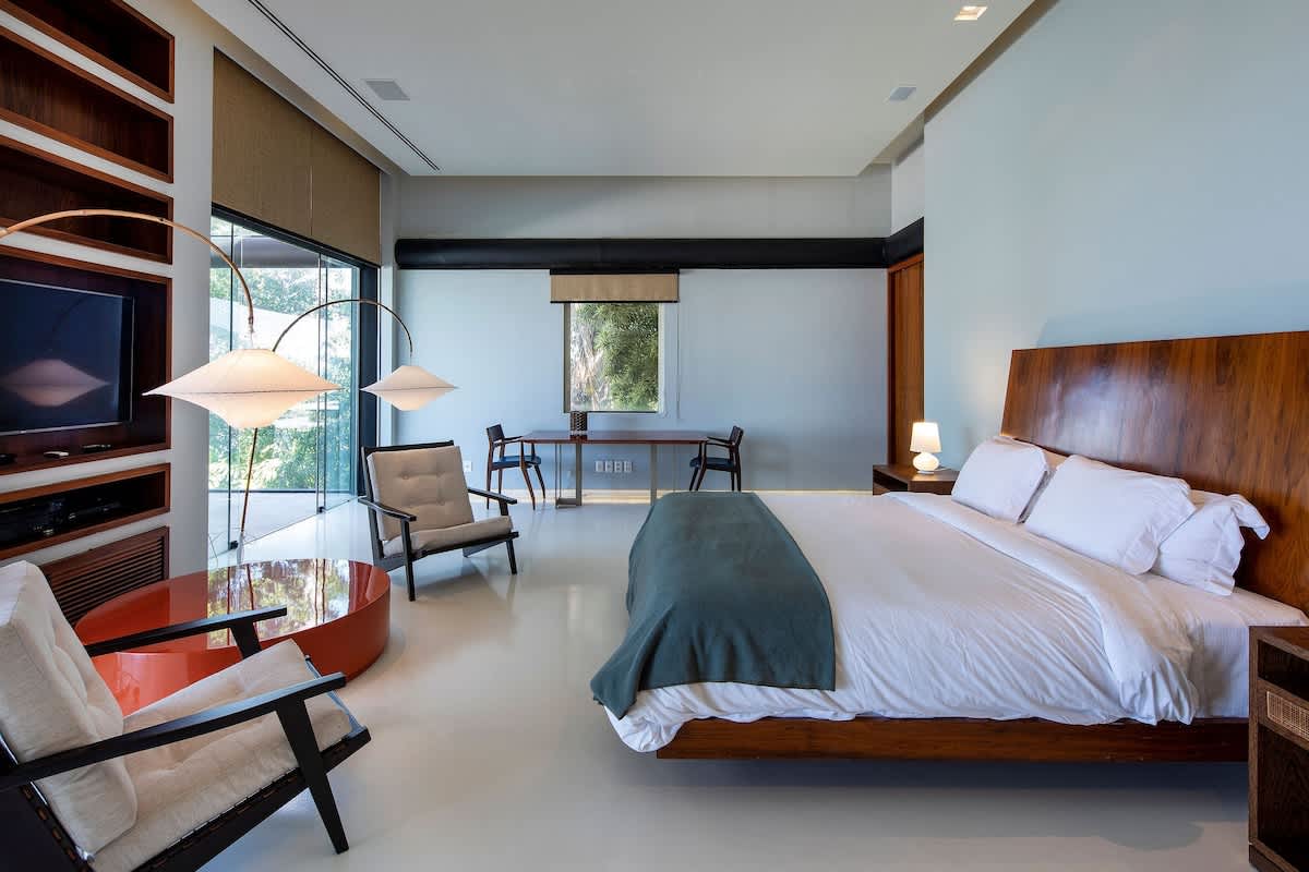 Master suite with carved-wood headboard and paired pendant lamps.